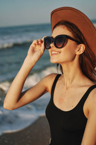 cheerful woman in sunglasses and a hat by the ocean walk summer - Fotografie, Obrázek