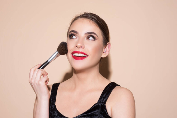 Beautiful woman holding makeup brush. Female skin care, close up face beauty portrait. Applying tone to skin. - Zdjęcie, obraz