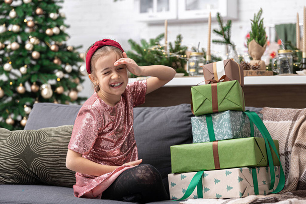 Een klein meisje wacht op het moment om haar kerstcadeaus uit te pakken.. - Foto, afbeelding
