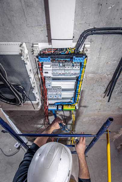 un elettricista maschio lavora in un centralino con un cavo di collegamento elettrico
. - Foto, immagini
