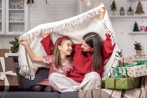 Mom and daughter on the couch in the room among the Christmas gifts. - Foto, immagini