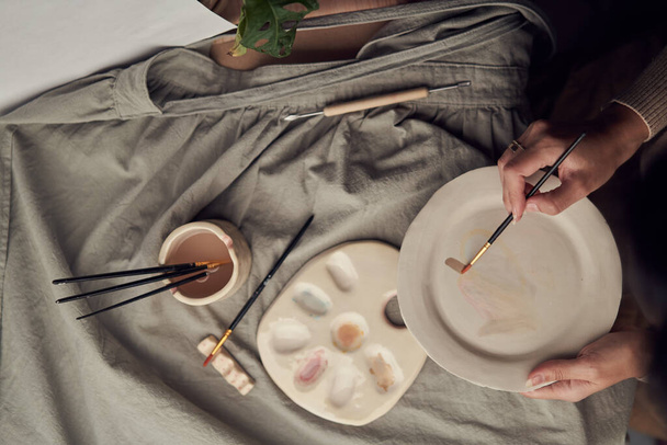 Anonymous craftswoman decorating ceramic plate - Valokuva, kuva