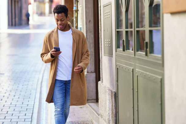 Jeune homme noir en utilisant son smartphone à l'extérieur. - Photo, image