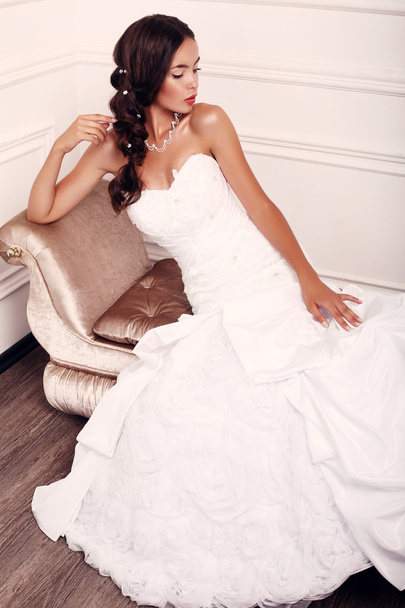 beautiful young bride with dark hair in wedding dress posing at studio - Foto, imagen