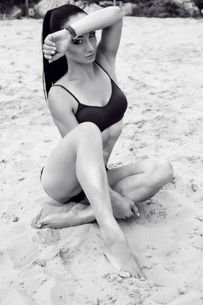 beautiful woman with dark hair in sportive clothes posing on beach - Foto, Imagem