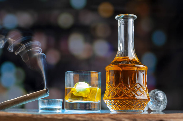A view of a decanter with whisky, glass, and a cigar near them - Photo, Image