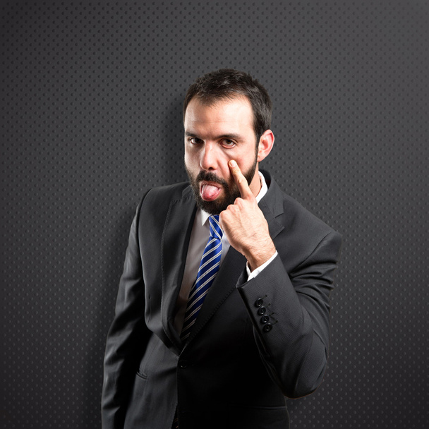 Young businessman making a mockery over black background  - Photo, Image