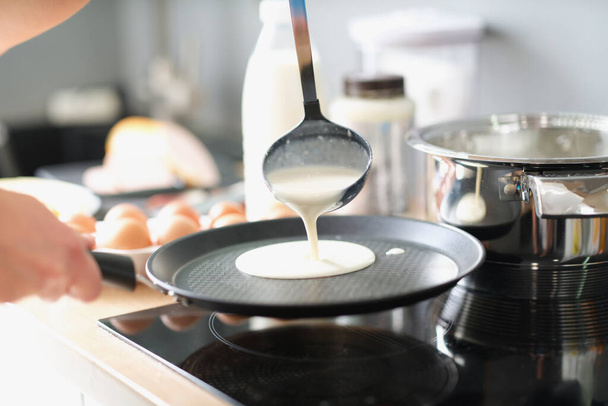 Ein Mann brät Pfannkuchen in einer Pfanne zu Hause in der Küche - Foto, Bild