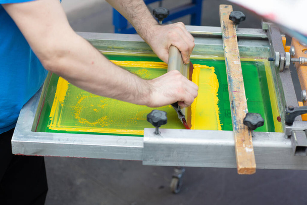 Сериграфический процесс шелкографии на швейной фабрике. Каркас, скребок и пластизол цвета красок - Фото, изображение