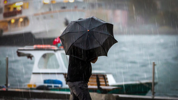 Mężczyzna trzymający parasol nad morzem w deszczowy dzień - Zdjęcie, obraz