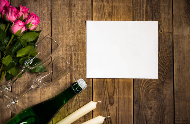 Closeup άποψη της ρομαντικής νεκρής ζωής σε ξύλινο τραπέζι με τριαντάφυλλα και σαμπάνια που βρίσκεται δίπλα σε κεριά - Φωτογραφία, εικόνα