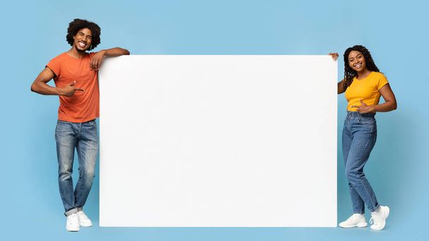 Stylish black people pointing at empty advertising board - Fotó, kép