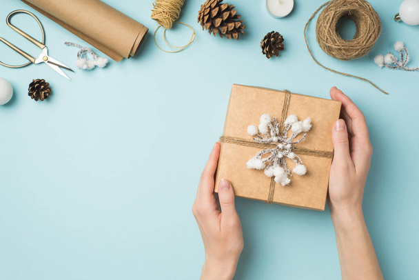 Kar dalı ve sicim Noel ağacı topları ile süslenmiş el sanatları el yapımı kağıt hediye kutusunu gösteren ilk kişinin fotoğrafı. El işleri araçları, kopyalanmış pastel mavi arka plan. - Fotoğraf, Görsel