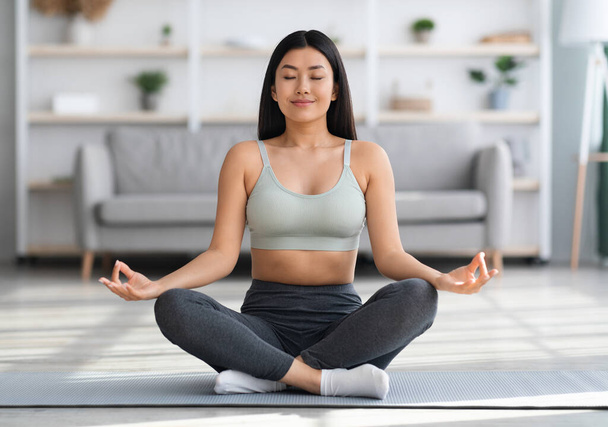 Reggeli meditáció. Fiatal, gyönyörű ázsiai hölgy jógázik otthon - Fotó, kép