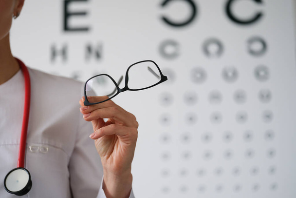Kadın doktor göz doktoru gözlük gösteriyor, yakın plan, bulanık - Fotoğraf, Görsel