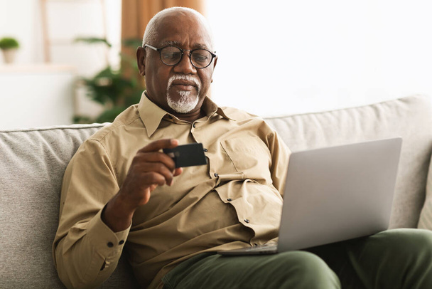 African Man Zakupy online za pomocą karty kredytowej i laptopa w pomieszczeniach - Zdjęcie, obraz