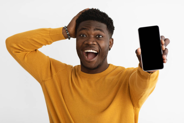 Šokovaný černoch ukazující smartphone s prázdnou obrazovkou - Fotografie, Obrázek