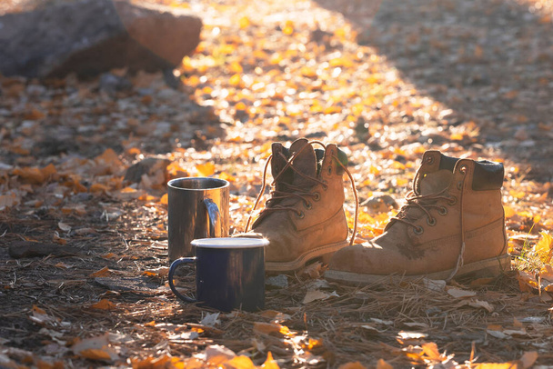 a camping aesthetics. cups with tea and boots in the dawn ligh - Foto, Imagem