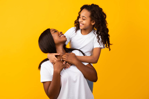African American mom and smiling daughter cuddling at studio - 写真・画像