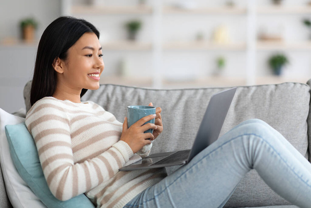 Domestic Leisure. Young Asian Woman Relaxing With Coffee And Laptop At Home - Photo, Image