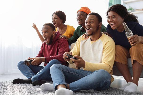 Amigos americanos africanos alegres jogando videogames em casa - Foto, Imagem