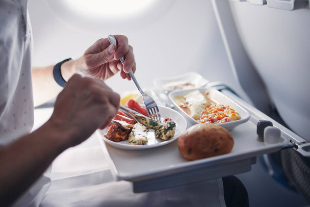 Passenger eating airline meal in airplane. Menu in business class on medium haul flight. - Zdjęcie, obraz