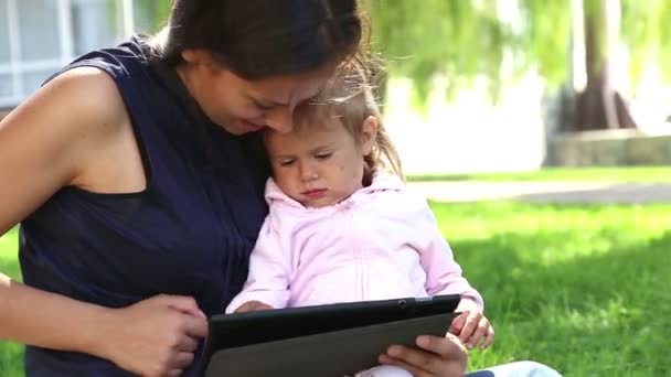 母は少し girl.mom tablet.young 母はラップトップで遊んで公園で赤ちゃんと一緒に演奏する子どもを教える教える. - 映像、動画