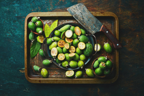 Feijoa. Fresh feijoa fruits on a tray. Top view, on a black stone background. - Фото, зображення