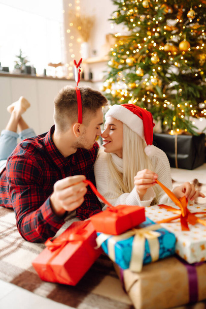A loving happy young couple enjoying time together near Christmas tree. Romantic day. Winter holidays. - Foto, afbeelding