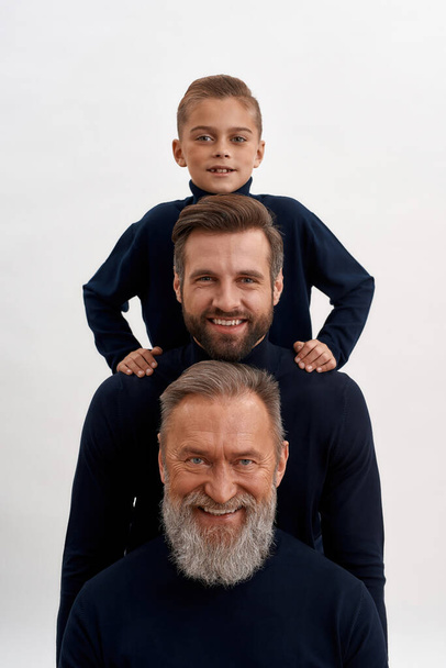 Narrow portrait of three generations of men posing - Foto, Bild