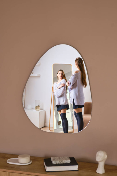 Reflection of young woman in wall mirror - Foto, imagen