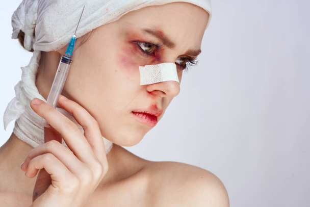 a person with bandaged face bruises syringe in hand painkillers studio lifestyle - Фото, изображение