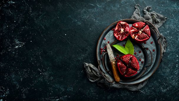 Ripe pomegranate. Pieces of juicy pomegranate on a plate on a dark wooden background. Free space for your text. - Foto, imagen
