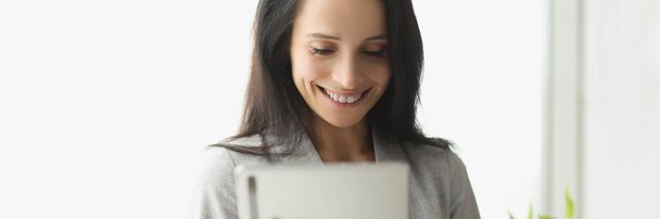 Mujer joven sonriente en traje sosteniendo tableta digital - Foto, Imagen
