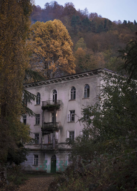Ruined and abandoned hous with beautiful architecture in the Akarmara mining village in Abkhazia. Ghost city in the evening autumn.  - Foto, Bild