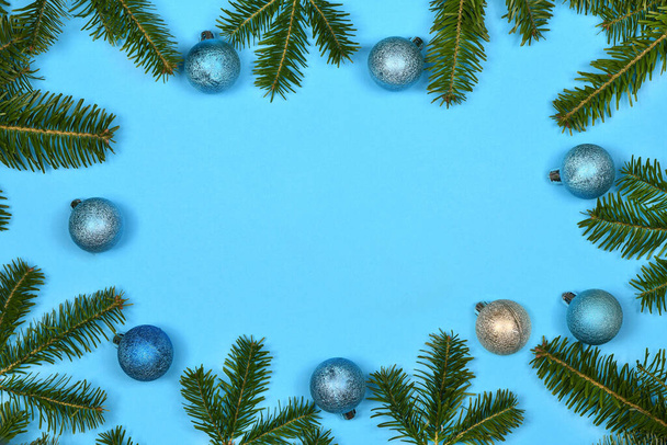 Елочная ветвь и рождественские украшения выделены на синем фоне. Фото высокого разрешения. Полная глубина резкости.  - Фото, изображение