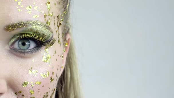 Demi-visage de femme caucasienne sexy avec art doré maquillage posant en studio
. - Séquence, vidéo