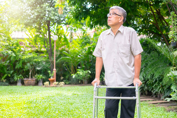 Щасливий старий азіатський чоловік використовує ходунки і ходить на подвір "ї. Концепція щасливого виходу на пенсію З обережністю з доглядальником і заощадженнями і старшим медичним страхуванням - Фото, зображення