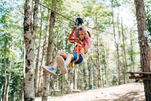 Junge steigt im Erlebnispark die Seilrutsche hinunter - Foto, Bild
