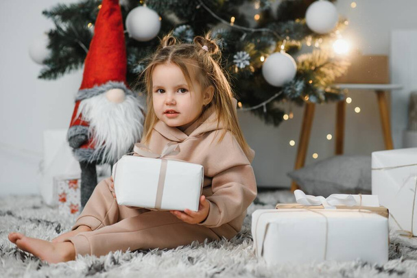 Onnellinen pieni hymyilevä tyttö joululahjalaatikolla. - Valokuva, kuva