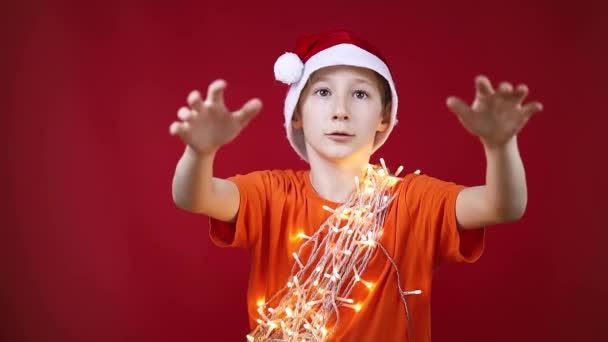 einem Jungen in Weihnachtsgirlanden wird ein Neujahrsgeschenk um den Hals geworfen - Filmmaterial, Video