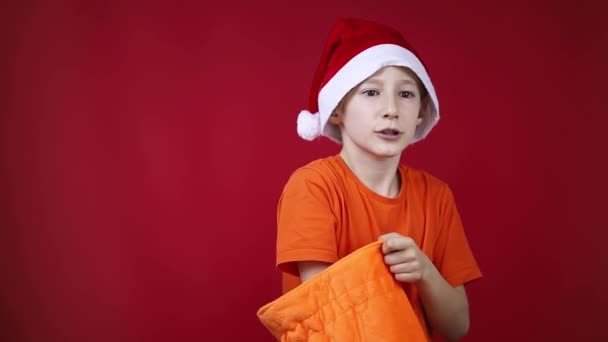 ein Junge mit Weihnachtsmütze sucht in einer Tüte nach Geschenken und findet sie nicht - Filmmaterial, Video