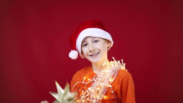 Junge mit Weihnachtsmütze hat einen Kranz um den Hals, der leuchtet - Filmmaterial, Video
