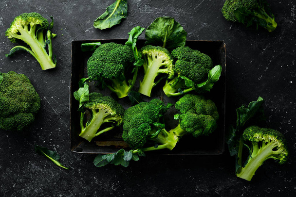 Verse groene broccoli in een houten doos. Bovenaanzicht. Op een zwarte achtergrond. - Foto, afbeelding