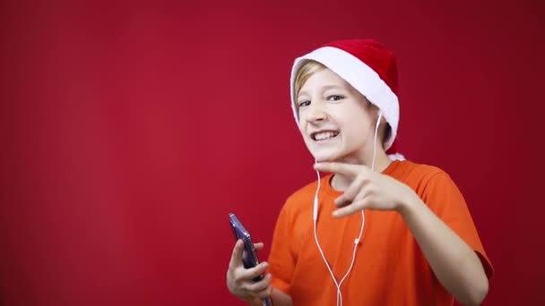 fiú egy karácsonyi kalap táncol és énekel rock zene mutatja heavy metal gesztusok - Felvétel, videó