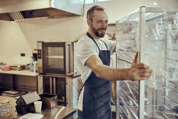 Travailleur masculin joyeux portant vitrine dans le café - Photo, image