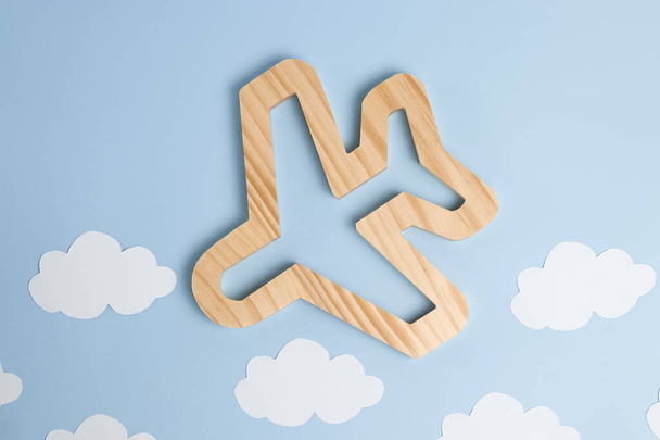 Light blue pastel background with white paper clouds and wooden plane in Scandinavian style. Concept for travel, recreation and travel abroad. - Photo, Image