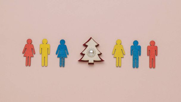 Eine Reihe bunter Menschenfiguren und ein Weihnachtsbaum auf pastellfarbenem Hintergrund. Das Minimalkonzept für das neue Jahr. Weihnachtsbaum. Zeitgenössische Kunst. - Foto, Bild