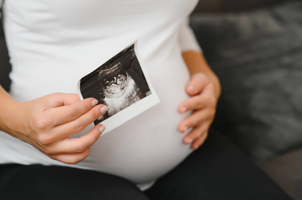 Pregnant women holding echo pictures in hand - Foto, afbeelding