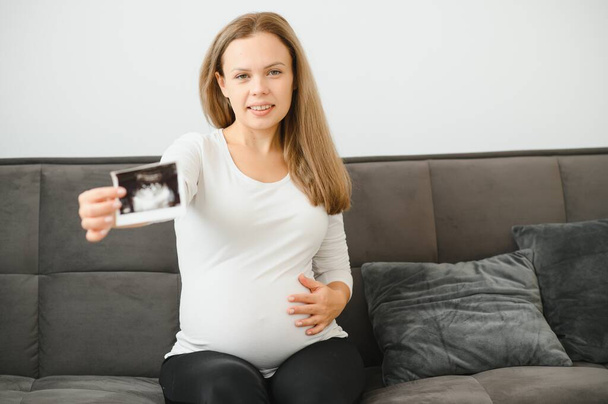 Pregnant women holding echo pictures in hand - Photo, image